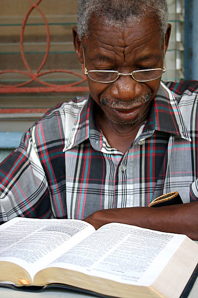 High angle shot of an unrecognizable senior man reading his book while sitting on a bench on the promenade at the beach