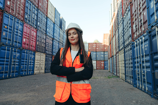 Portrait of Caucasian Woman Confident Engineer Worker on Delivery terminal, Standing outdoors in white Hard Hat and Vest.