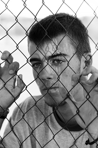 Teenager behind a wired fence. Black and white photo