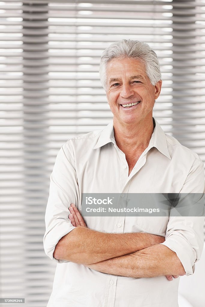 Sorrindo homem sênior em pé com os braços cruzados - Foto de stock de 60 Anos royalty-free