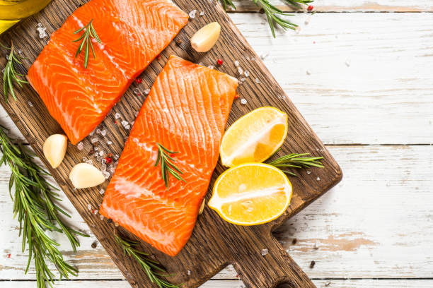 Salmon fish with ingredients at white table. Salmon, fresh salmon fillet at cutting board with ingredients for cooking. Top view with copy space. salmon stock pictures, royalty-free photos & images