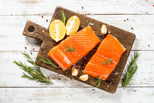 Salmon, fresh salmon fillet at cutting board with ingredients for cooking. Top view with copy space.