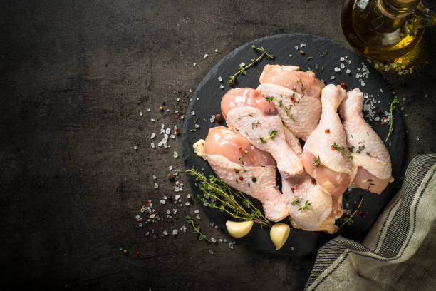 istock Chicken drumsticks with herbs at black. 1739097836