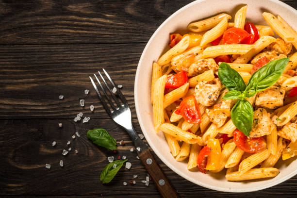 istock Pasta with chicken and vegetables at wooden table. 1739102255