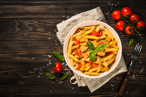 Pasta with chicken and vegetables at wooden table. Traditional italian food. Top view.