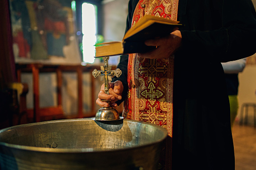 Close-up of Orthodox priest holding the cross and the Bible in Orthodox church