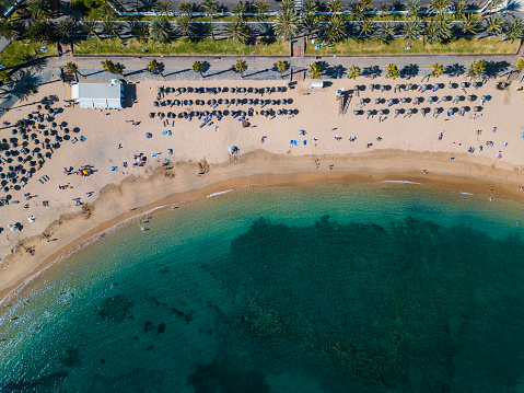 exotic sea shore with travellers, azure water, crowd under umbrellas, Tenerife, Canary Islands