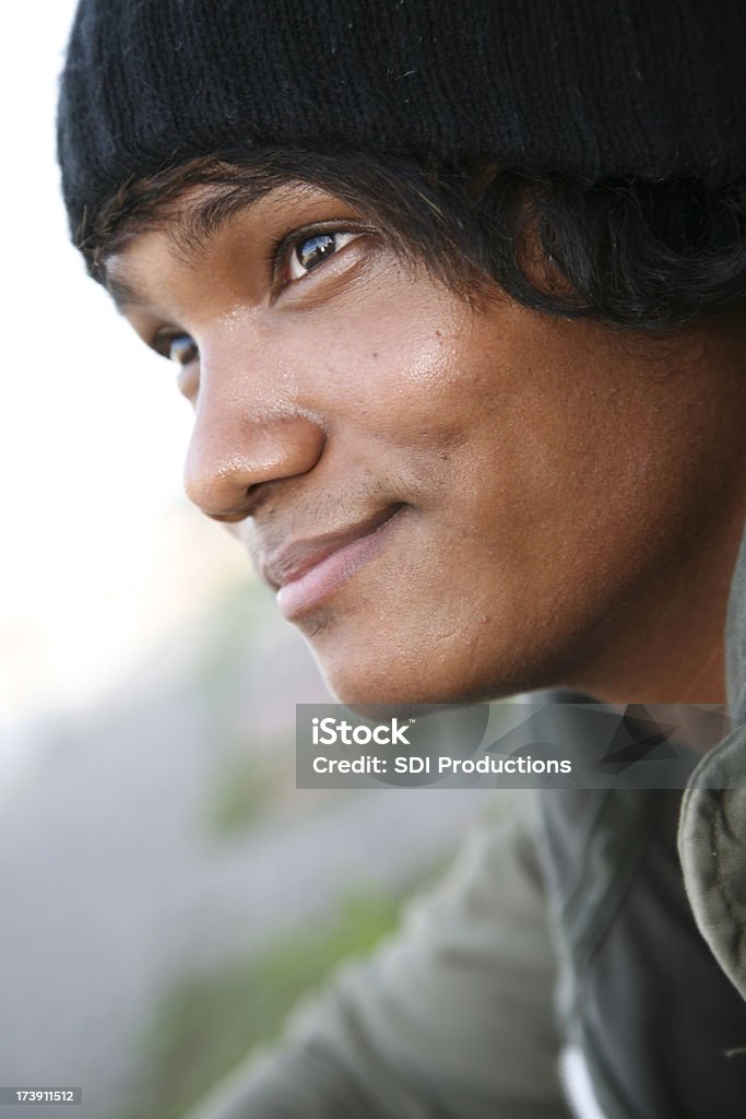 Ritratto di un sorridente giovane uomo seduto sul bordo del marciapiede - Foto stock royalty-free di Abbigliamento casual