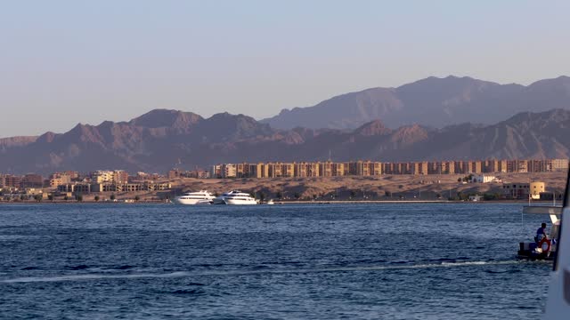 Boating in the Red Sea with desert city and yachts in the background