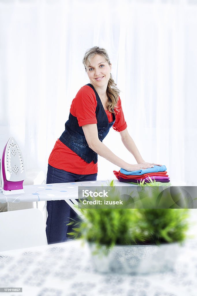 Joven mujer planchado de ropa y plegable - Foto de stock de 20-24 años libre de derechos