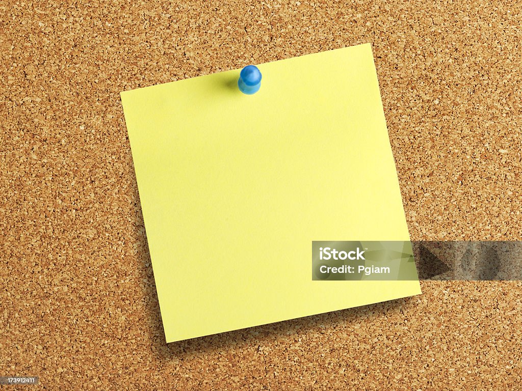 Cork background with a yellow post it note Office bulletin board message Adhesive Note Stock Photo