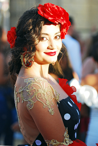 Young and beautiful andalusian woman wearing an awesome hairstyle with fresh roses during the Flamenco open festivities that take place every year in May during the local holidays in Jerez de la Frontera.