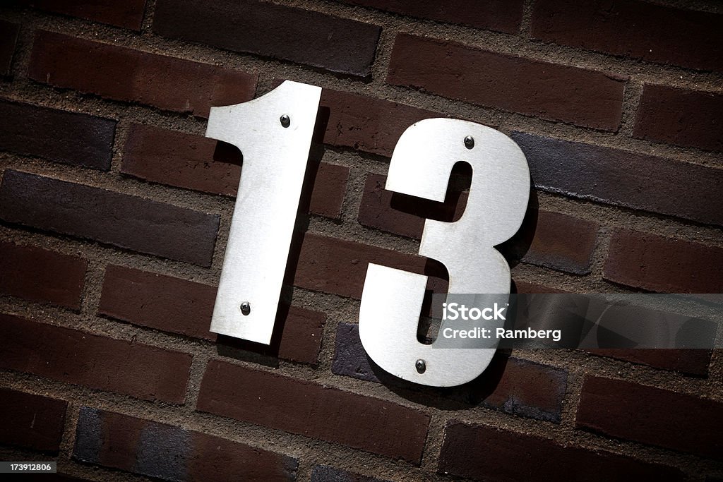 Number 13 Metal plate number 13 on a brick wall. House Address Stock Photo