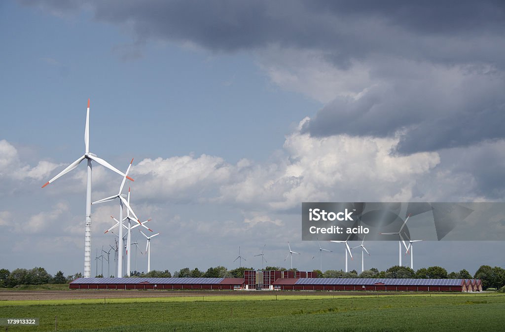 Wind turbines detrás de una moderna de granja con paneles solares - Foto de stock de Central eléctrica solar libre de derechos