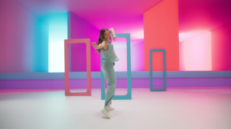 Beautiful Woman with Bright Makeup Dancing Energetically and Interacting with Colorful Geometric Abstract Environment. Creative Young Female Happily Performing Modern Dance Choreography in a Studio