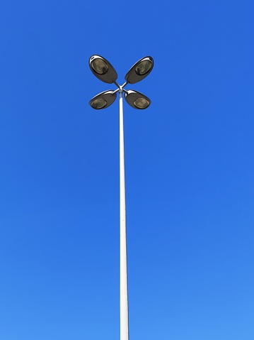 Tall street lights hanging on the metal pole front of the blue sky