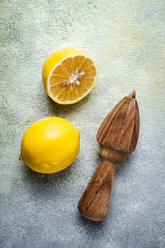 Wooden citrus reamer, manual lemon juicer, made of acacia wood, with citrus fruits on the table, top view,