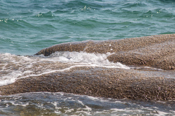 Waves hitting on rocks and crashing on beach in Greece. Natural wild beach