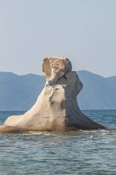 istock Rock shaped like elephant on beach in Greece surrounded by ocean. Interesting natural rock structure. Visible mountains in the baackground 1739146625