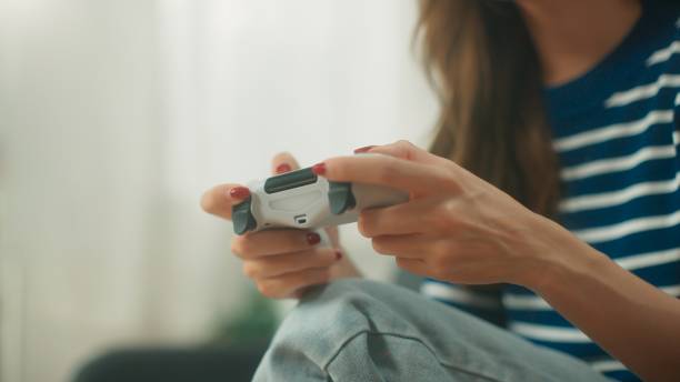 istock Happy young Asian woman holding wireless controller joystick playing exciting video game sitting on comfortable sofa in living room, Woman enjoying with activities at home 1739147028
