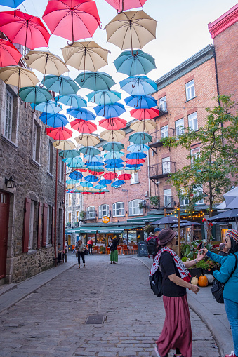 Happy Tourists on a Street with a Canopy of Colorful Umbrellas and Lined with Restaurants in the Petit Champlain Area of Quebec City