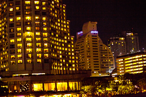 Illuminated Bangkok skyline around Center Point Hotel near Chao Praya River and Saphan Taksin bridge
