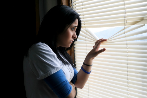 Sad young woman looking out of window.