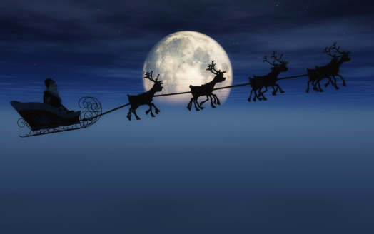 Santa on his sleigh pulled by 8 reindeer in front of a large moon and fog.