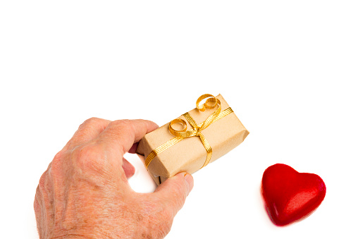 Gift box wrapped in brown paper over white background and a red object in heart shape over white background.Conceptual image for Valentine's day -holiday. Image shoo.t in studio