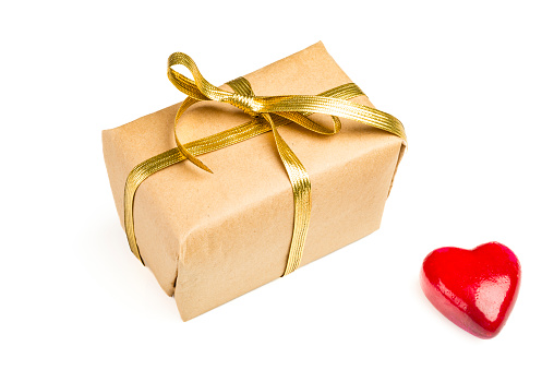 Gift box wrapped in brown paper over white background and a red object in heart shape over white background.Conceptual image for Valentine's day -holiday. Image shoo.t in studio