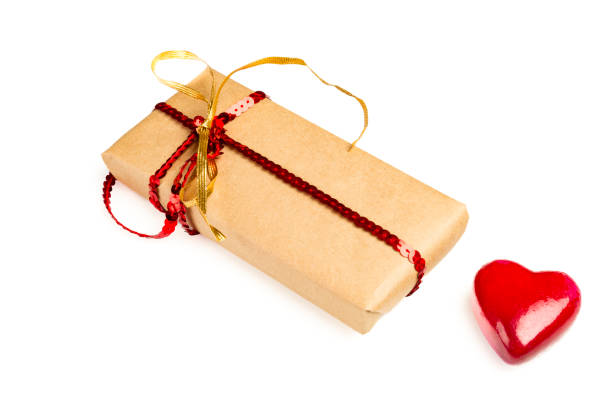 Gift box wrapped in brown paper over white background and a red object in heart shape over white background.Conceptual image for Valentine's day -holiday. Image shoo.t in studio