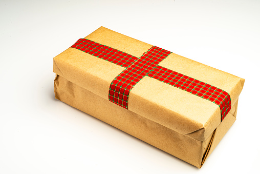 Close up view of gift box with ribbon wrapped in a brown paper  on white background.Conceptual image for Valentine's holiday or Christmas-holiday.