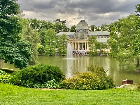 Belvedere Baroque palace in Vienna seen from the public gardens with fountains and dark clouds above.