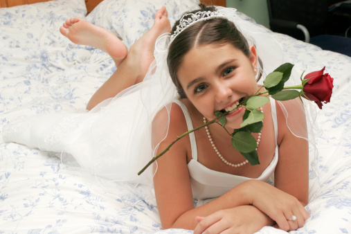 a girl biting a rose in her communion dress