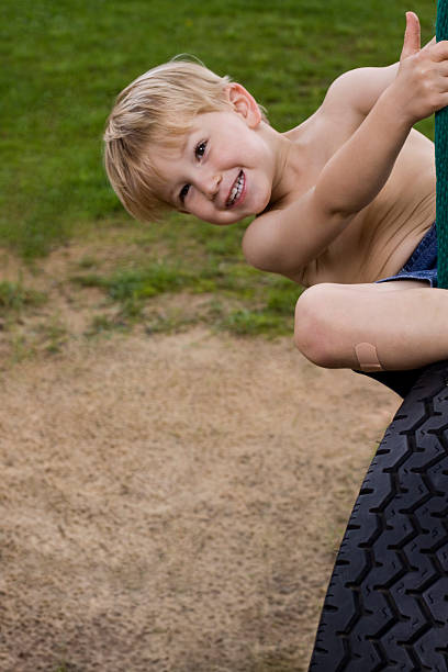 Smiling Little boy Having fun on tire swing stock photo