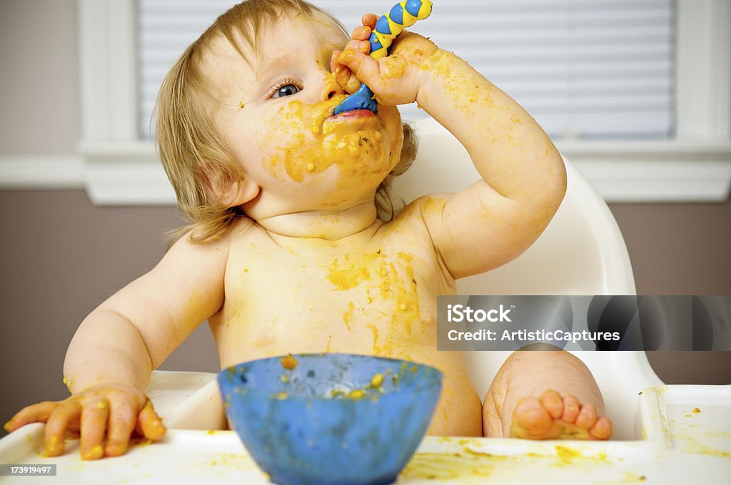 Беспорядочным ребенок ест питание в Высокий детский стульчик - Стоковые фото Беспорядок роялти-фри