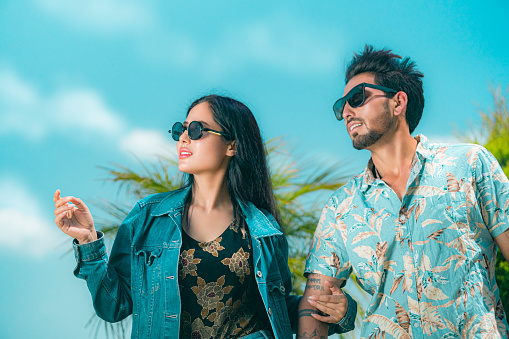 An Asian/Indian attractive couple enjoys outings on holiday wearing sunglasses on sunny days.