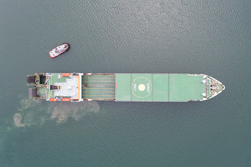 Top view of Ro-Ro ship approaching to the port with tug boat assistance and pilot boat.