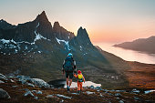 Family hiking travel: father and child with backpacks exploring mountains of Senja island in Norway adventure healthy lifestyle outdoor active vacations together man with kid trekking