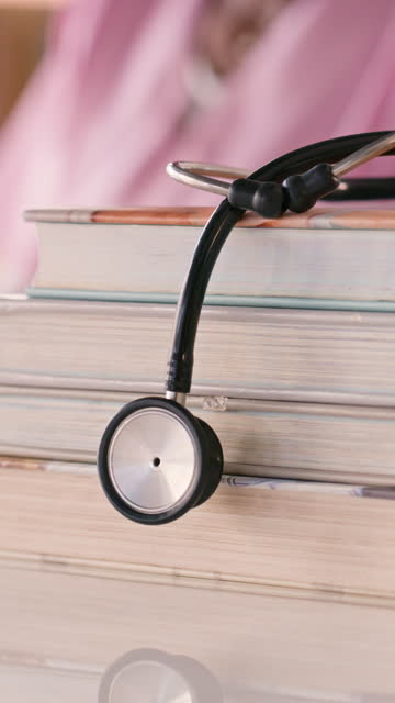 Books, stethoscope and closeup of student at table for education, learning and studying health. Medical professional tools of doctor, stack of textbooks and research knowledge at university college