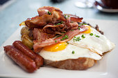 A closeup of eggs, bacon, ham, and sausage on top of toast