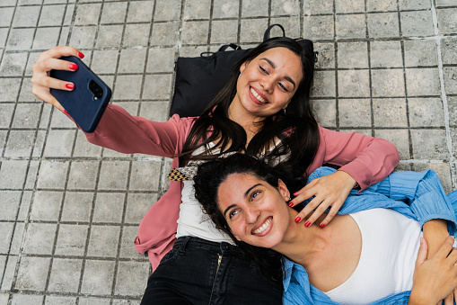 Young friends taking a selfie lying down on floor outdoors