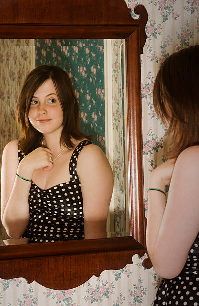 istock young woman looking in mirror 173922808