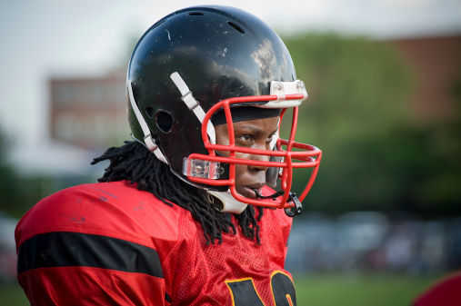 Candid of African American female football player during game. She plays women's tackle football as a quarterback.