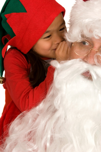 Asian girl dressed up like elf whispering in Santa's ear