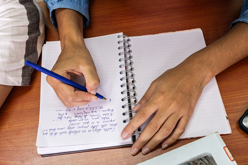 Close-up of a student writing on a note book at university