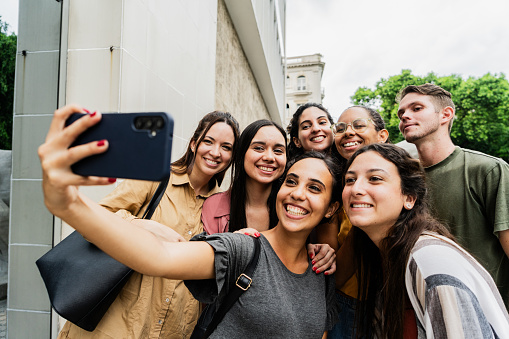 Young friends taking a selfie using mobile phone at street