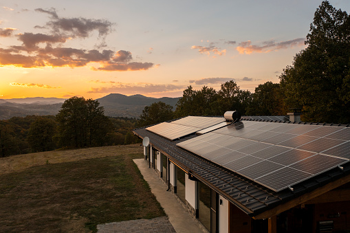 Aerial view of solar powered house in nature shot at sunset.