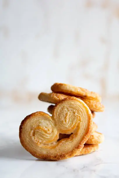 Close up of Puff pastry palmiers on a white marble table. Homemade bakery for breakfast. Vertical picture.