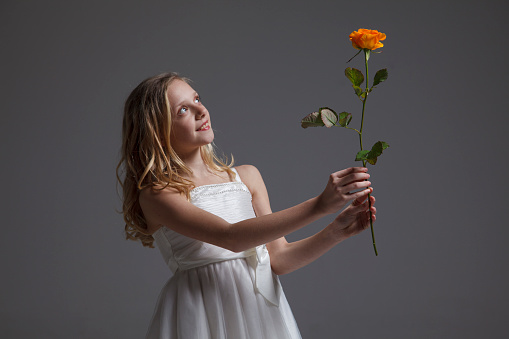 Girl giving rose for mother's day, birthday or valentine's day. Isolated on dark background.